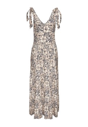 Frau steht am Pool und trägt ein ärmelloses Maxikleid mit Blumenmuster, mit gebundenen Trägern an den Schultern und Sandalen.