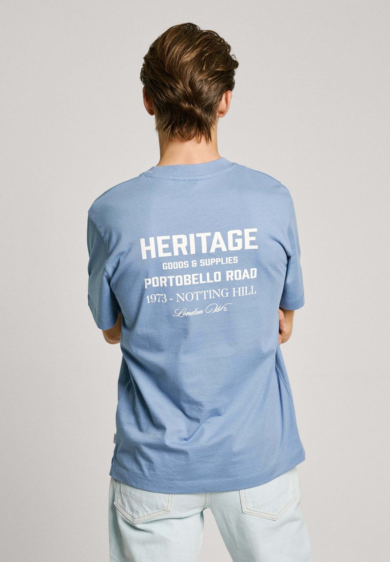 Light blue cotton T-shirt with short sleeves, featuring a white printed design on the back that includes text and accents.