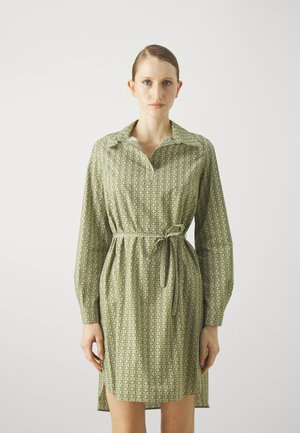 Vihreä kuviollinen paitamekko, jossa on kaulus, pitkät hihat ja solmittava vyötärö. Kankaassa on toistuvia logokuvastoja.