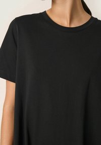 Czarna koszulka z krótkim rękawem z okrągłym dekoltem. Wykonana z gładkiej, lekkiej tkaniny o luźnym kroju.