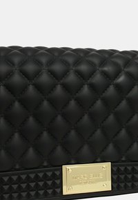 Borsa a tracolla nera trapuntata con finitura opaca, targhetta logo in metallo dorato e fondo testurizzato con borchie a piramide.