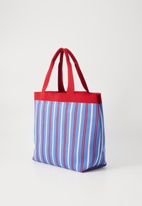 Borsa tote a righe con strisce verticali blu e bianche, dettagli rossi, manici robusti e forma rettangolare. Realizzata in tessuto resistente.