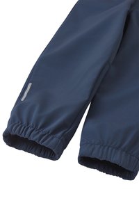 Navy blue waterproof pants with elasticated cuffs, featuring smooth texture and reflective logo accent on the side. Suitable for outdoor activities.