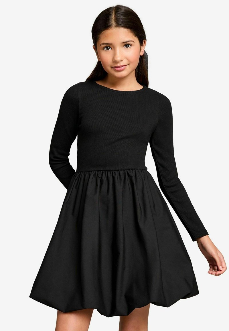 Schwarzes Kleid mit langen, schmalen Ärmeln, einem gerippten Oberteil und einem gerafften, voluminösen Rock. Besitzt einen runden Halsausschnitt und eine feste Textur.