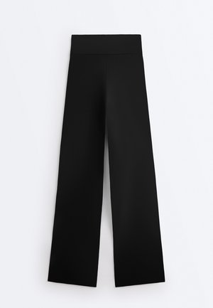 Čierne nohavice s širokými nohavicami a vysokým pásom, hladká látka bez viditeľných vreciek alebo ozdôb.