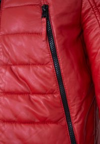 Rote Lederjacke mit gestepptem Muster, ausgestattet mit einem schwarzen Reißverschluss und einer taillierten Passform. Keine zusätzlichen Patches oder Akzente sichtbar.