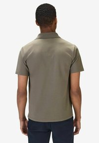 Kortärmad olivgrön pikétröja med klassisk krage och en mjuk textur. Synlig söm vid fållen och ärmsluten.