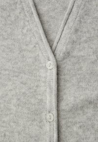Cardigan gris tricoté avec un col en V, doté d'un seul bouton blanc, d'un tissu texturé et de bords côtelés.