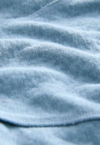 Tejido suave de color azul claro con una superficie texturada y ondulada; cuenta con un tejido fino y un ligero estiramiento; sin patrones ni herrajes visibles.