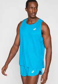 Σετ αθλητικό τοπ και σορτς σε τιρκουάζ, κατασκευασμένο από ελαφρύ υλικό, με μικρό λευκό λογότυπο, απαλό ύφασμα και άνετη εφαρμογή.