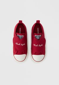 Κόκκινα υφασμάτινα παπούτσια τύπου slip-on με καρδιόσχημο σχέδιο στο μπροστινό μέρος και λευκές λαστιχένιες μύτες. Διαθέτουν το κέντημα «Chuck Taylor» σε λευκό χρώμα.