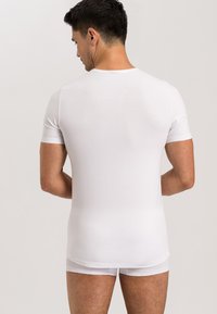 Biała krótki rękaw t-shirt z okrągłym dekoltem, dopasowany krój, gładka faktura i prosty dół, noszony na dopasowane białe majtki.