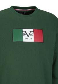 Grüner Sweatshirt mit einem rechteckigen Grafikdesign, das die italienische Flagge und den Text "1969" zeigt. Material ist ein Baumwollmix, mit einem gerippten Kragen.