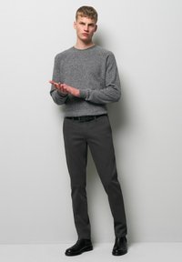 Gray knit sweater with round neck, paired with dark gray slim-fit trousers. Black ankle boots and a black belt complete the look.