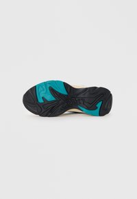 Suela de zapato con una base de goma negra con un patrón texturizado, acentuada por detalles en aqua y crema. Diseñada para ofrecer agarre y estabilidad.