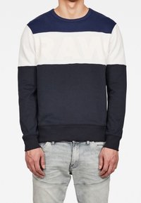 Sudadera azul marino y crema con cuello redondo, que presenta un gran logo "RAW" en el pecho en un color contrastante. Material de mezcla de algodón.