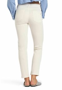 Witte skinny jeans met een gladde textuur, hoge tailleband en twee achterzakken. Gemaakt met grijze instappers en een blauwe knopshirt.