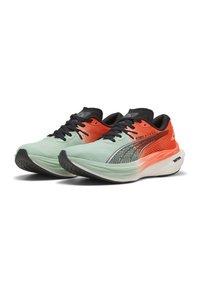 Zapatillas de correr con una parte superior de malla en verde menta, acentos en negro, un talón en degradado naranja y una suela de goma negra texturizada.
