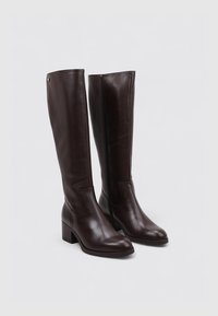 Brown leather knee-high boots with a square toe, block heel, and minimal stitching. Side zip closure and smooth finish.