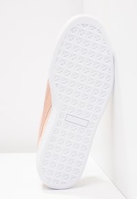 Rosa Wildleder-Schuhsohle mit einer weißen Gummisohle, die ein strukturiertes Diamantmuster und ein sichtbares Logo aufweist.