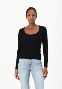 Sorte langermet ribbestrikket topp med rund hals, kombinert med lyseblå jeans. Stoffet har en glatt tekstur og en tettsittende design.