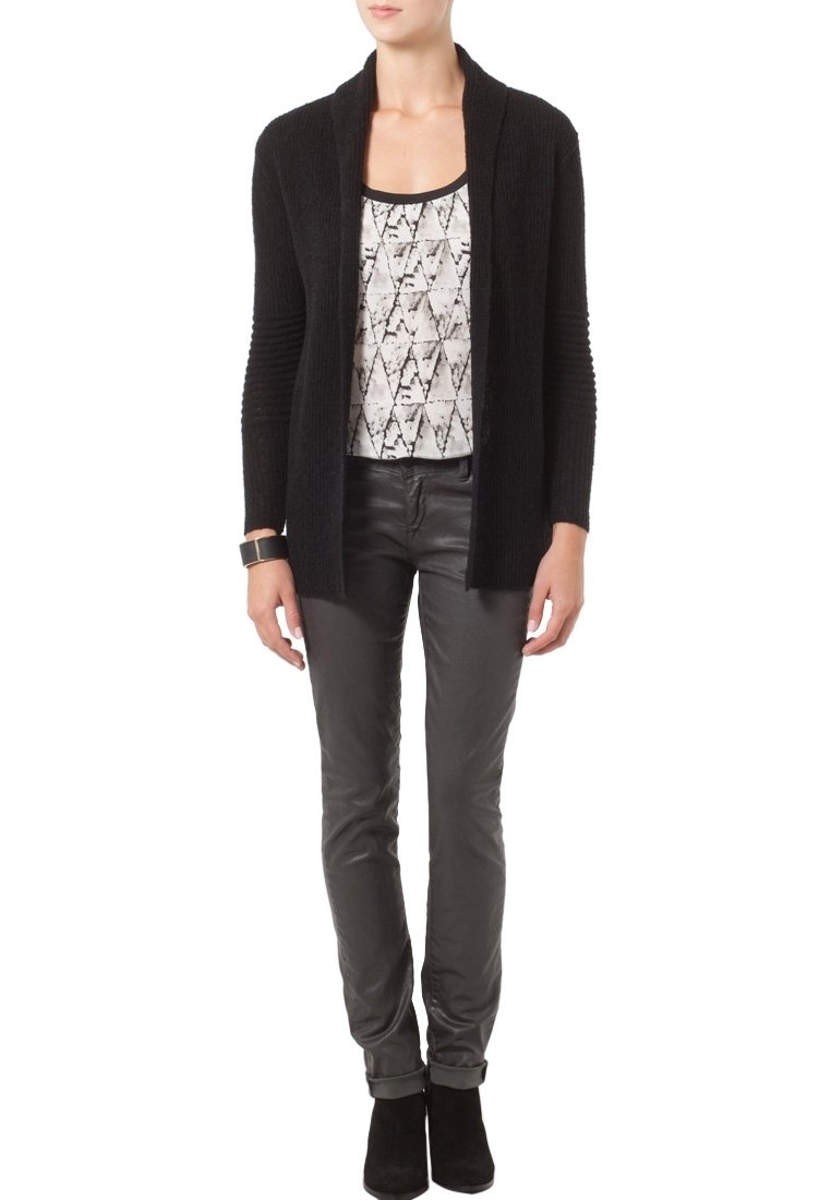 Černý žebrovaný cardigan s otevřeným předním dílem, vrstvený přes vzorovaný top v bílé a šedé. Spárováno se slim-fit šedými kalhotami a kotníkovými botami.