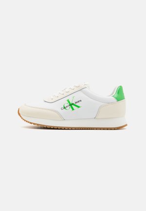 Biało-beżowy sneaker z zielonym elementem na pięcie i zielonym logo "CK Calvin Klein Jeans" po boku, z białymi sznurowadłami i gumową podeszwą.