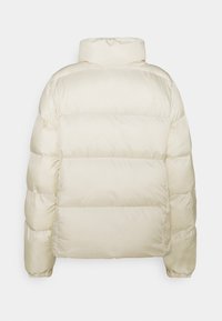 Chaqueta de plumón color crema con cuello alto, diseño acolchado y almohadillado. Presenta puños elásticos y patrón liso, proporcionando calidez y cobertura.