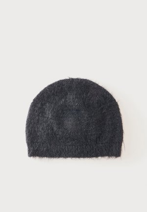 Schwarze flauschige Strickmütze mit weicher, strukturierter Oberfläche und abgerundeter Form auf schlichtem weißen Hintergrund.
