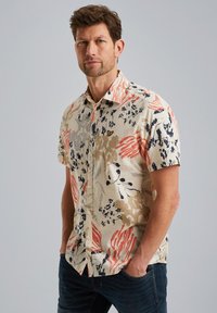 Lyhythihainen paita, jossa on beige tausta ja kukkakuosia punaisella, tummansinisenä ja harmaana, valmistettu kevyestä kankaasta.