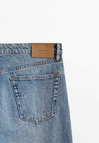 Ljusblå denimjeans med en läderlogotyp, bakficka med söm detaljer och rakt snitt.