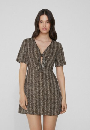 Vestido de leopardo, de manga corta, con un escote en V profundo y detalle de lazo en la parte delantera. Textura fluida, cintura ajustada y falda acampanada.