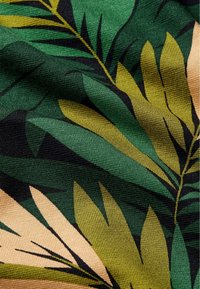 Tessuto in fibra con un motivo a foglia nelle tonalità di verde, oliva e beige. Tessitura testurizzata che offre profondità e interesse visivo.