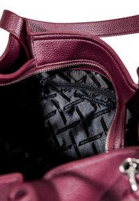 Borsa in pelle borgogna con esterno testurizzato, chiusura zip e interno in tessuto nero con motivo a logo ripetuto.