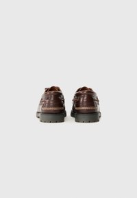 Scarpe in pelle marrone con una texture liscia, suola in gomma e cuciture a contrasto. Presentano un design in stile mocassino con punta arrotondata.