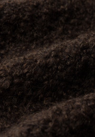 Tissu tricoté marron avec une surface douce et texturée, présentant une apparence légèrement floue et des plis irréguliers en couches.