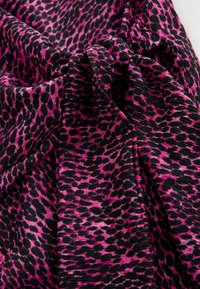 Leopardmönstrad tyg med en livlig rosa och svart färgskala, med en mjuk, texturerad yta och tydliga mönsterdetaljer.