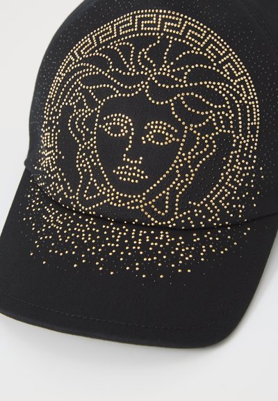 Svart keps med en guldbelagda Medusa-design med en texturerad finish och böjd skärm, prydd med ett geometriskt mönster på den övre bandet.