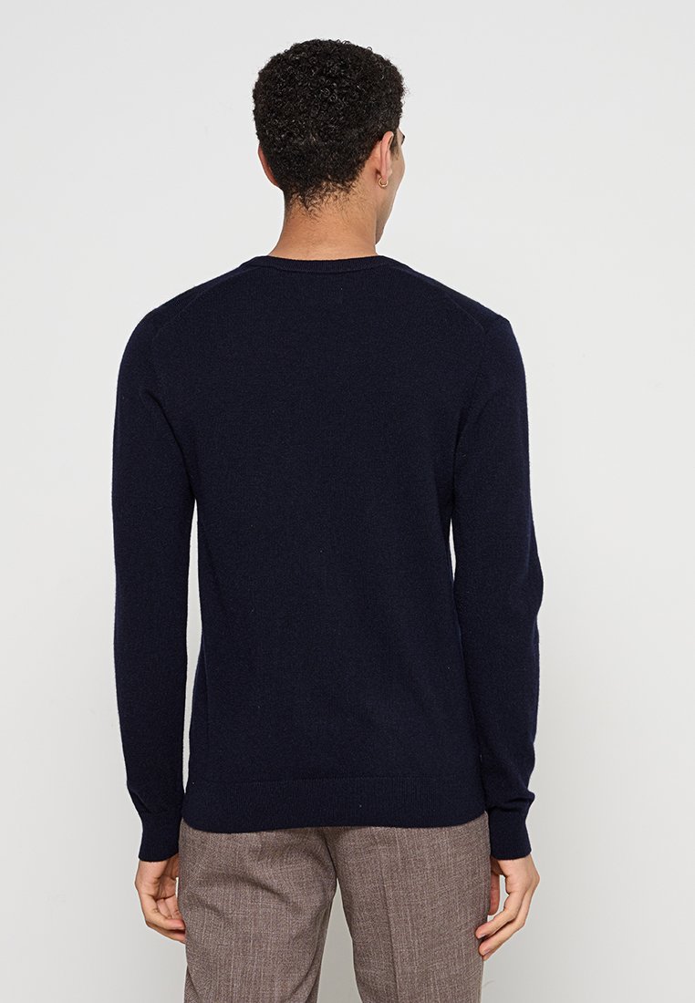 Marineblaues Strickpullover mit langen Ärmeln, rundem Halsausschnitt und gerippten Bündchen. Aus weichem, strukturiertem Material hergestellt, geeignet zum Übereinandertragen.