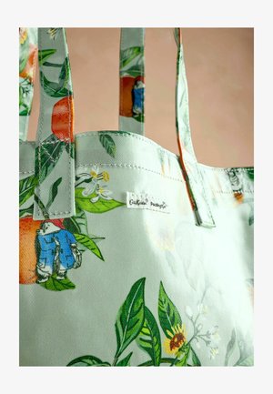 Hele rohelise tooni kandekott, millel on lillemustrid, erksate oranžide ja kollaste lilledega, roheliste lehtede ja küljele õmmeldud sildiga.