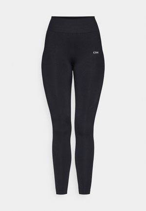 Leggings noirs avec une taille haute, fabriqués à partir d'un tissu lisse et extensible. Présente un petit logo près de la taille.