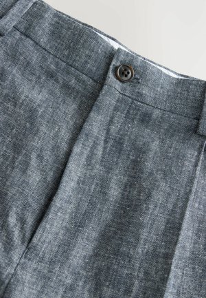 Grå linnbyxor med en slät yta, med en knappstängning i midjan och subtila diagonala linjer i tyget.