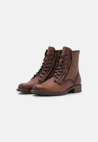 Stivaletti in pelle marrone con finitura texturizzata, lacci frontali e zip laterale. Progettati con tacco basso e dettagli a motivi.