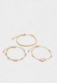 Kolme herkkiä kultaketjun rannekorua; yksi käärmeenketju, yksi kristallikoristeilla ja yksi kukkamuotoisella riipuksella.