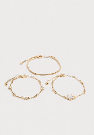 Kolm delikaatset kuldset käevõru ahelate ringidega; üks rästikuahelaga, üks kristallaktsentidega ja üks lillekujundi charmiga.