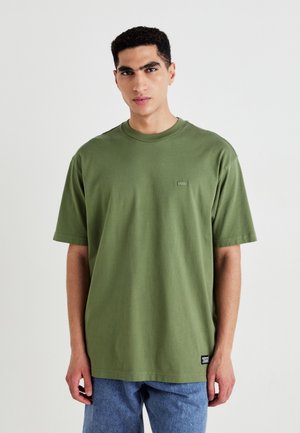 Olive green cotton t-shirt with a round neck and short sleeves; features a small logo patch on the chest and a relaxed fit.