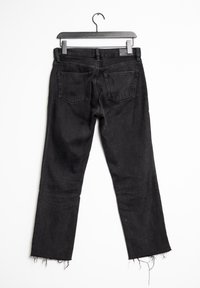 Jeans in denim nero con gamba dritta, orli sfilacciati, design a cinque tasche e vita media, appesi a una gruccia nera su uno sfondo bianco.
