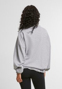 Oversized gray sweatshirt with ribbed balloon sleeves and a raw hem. Soft fabric texture; relaxed fit, ideal for casual wear.