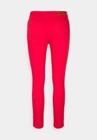 Vaqueros skinny rojos con una textura suave, que cuentan con dos bolsillos traseros y un parche de cuero en la cintura. Forma ajustada, tejido elástico.