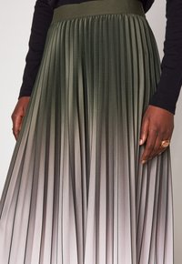 Gonna plissettata in tonalità di verde scuro e grigio, con una cintura ampia e pieghe verticali, caratterizzata da una finitura liscia e strutturata.